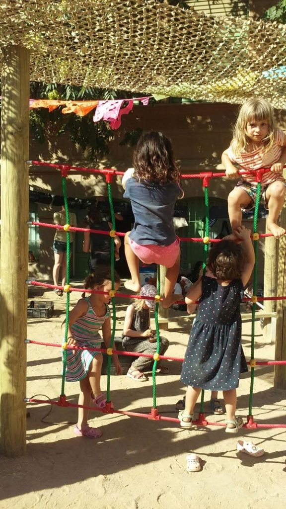 Una imatge on es veu a la mainada jugant amb la xarxa que han construit la comissió "Patis d'escola" al pere Vila